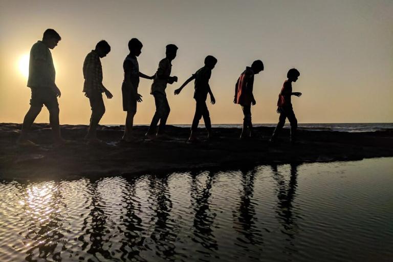 Silhouetted children walking near water